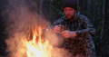 Man with cup of tea the fire in the forest. Human looks at the bonfire and drinks tea on nature.  - PhotoDune Item for Sale