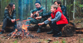 Father is playing guitar while his children and wife frying a meat. Family sits around a campfire.  - PhotoDune Item for Sale