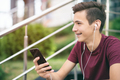 A smiling young man with a smartphone, in the street.  Happy teenage boy is using mobile phone.  - PhotoDune Item for Sale