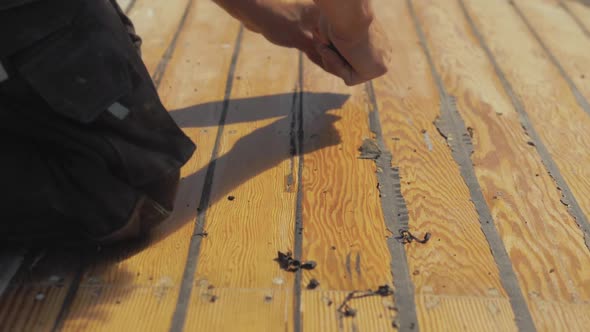 Using scraping tool to res excess mastic sealant on pine planking boat roof restoration. SLOW MOTION
