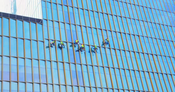 Six Men Workers in Red and Yellow Work Clothes Cleaning the Exterior Windows of a Business