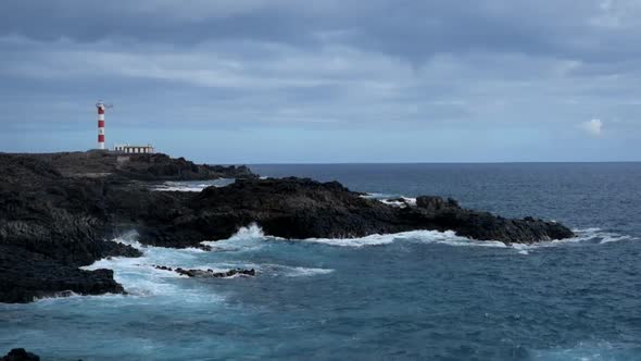 Old classic style lighthouse on the coast of the ocean with wind and clouds in movement