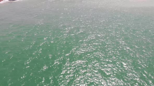 Aerial Over Turquoise Ocean Revealing Balochistan Coastline. Dolly Forward, Tilt Up