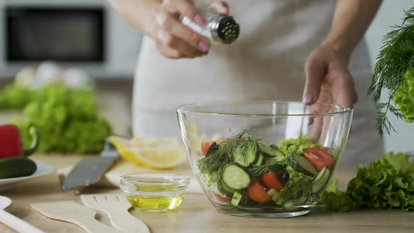 Woman Adding Salt in Salad With Vegetables in Glass Bowl, Close-Up Video