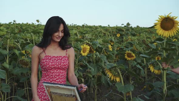 Handsome Man Comes and Presents Sunflower to His Painting Girl in Field