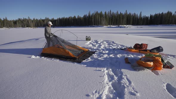 Man setting up his tent in the snow.