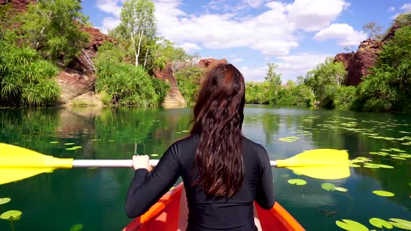 Women canoeing down scenic river oasis in remote Australian Outback.