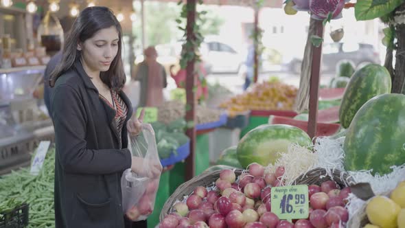 Young attractive woman shopping at the greengrocer choosing apple