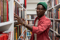 African guy University student standing between bookshelves in library - PhotoDune Item for Sale