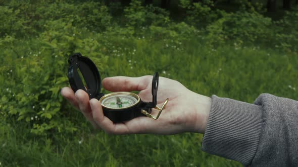 A man with a compass in his hands is looking for a way. Forest.