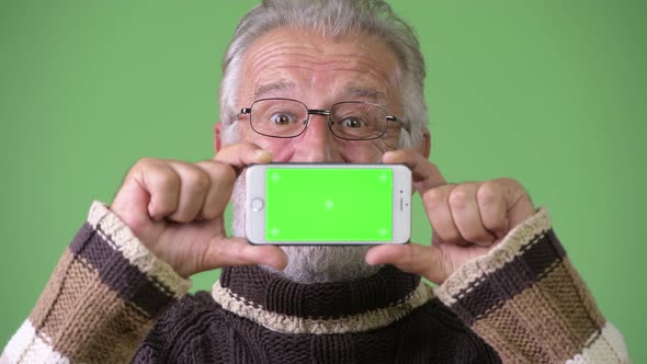 Handsome Senior Bearded Man Wearing Warm Clothing Against Green Background