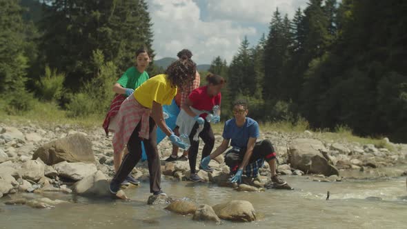 Ecologically Aware Diverse Multiethnic People Doing Environmental Cleanup on Mountain River