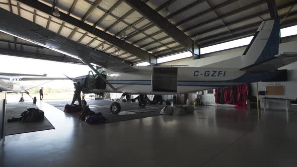 A white passenger plane parked in a small airplane hangar.