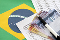 Pen with Brazilian money bills on blank of lottery game. Concept of luck and gambling in Brazil - PhotoDune Item for Sale