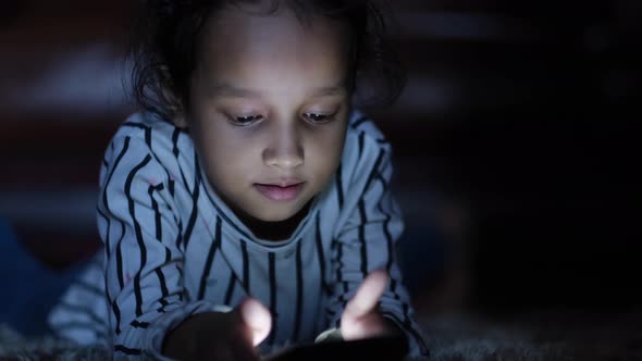 Child Girl Laying on Floor Using Smart Phone at Night