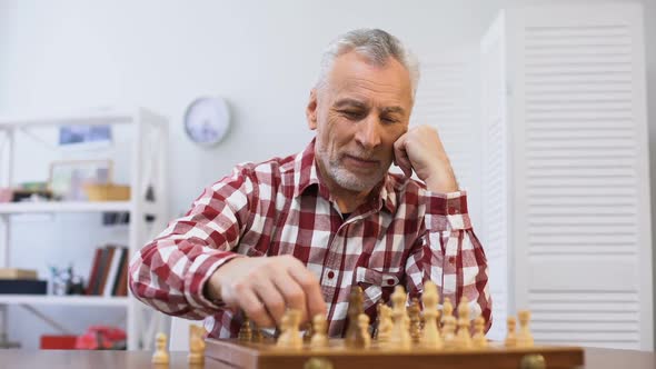 Elderly Male Playing Chess Alone and Looking to Camera Preparing for Competition