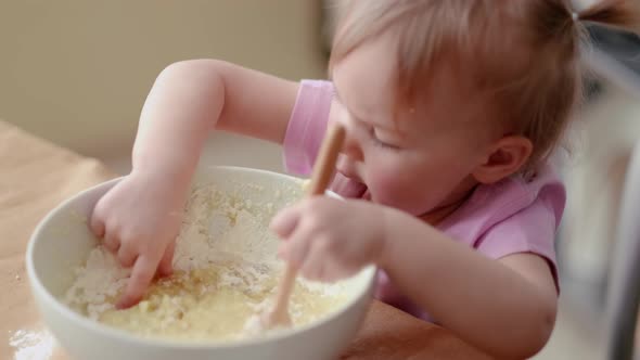 Little Cute Funny Girl Licking the Dough From Her Finger Helping Mother Prepare Pie Cake in Kitchen