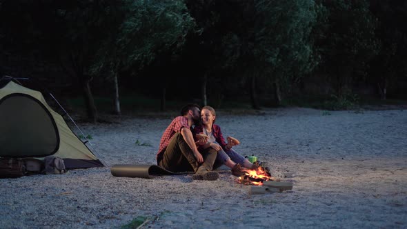 Happy Tourist Couple Camping in the Wild Eating Hot Dogs and Kissing