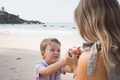 Little son presents flower to mother at beach in sunny summer day - PhotoDune Item for Sale