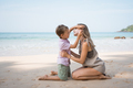 Little boy gives young beautiful mother flower at sea beach in sunny summer day - PhotoDune Item for Sale