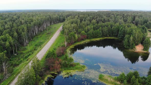 Aerial Motion Above Blue Pond Near the Country Road and Birds Flock Flies Over Pond Russia