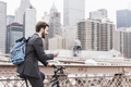 USA, New York City, businessman on bicycle on Brooklyn Bridge using cell phone - PhotoDune Item for Sale