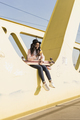 Young woman sitting on bridge using smartphone - PhotoDune Item for Sale