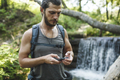 Young man holding cell phone at a waterfall in forest - PhotoDune Item for Sale