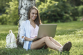 Smiling young woman using laptop on a meadow - PhotoDune Item for Sale