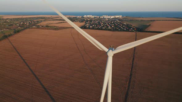 Aerial View of a Windmill Against the Township and Farmland on a Beautiful Summer Evening