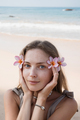 Beautiful young adult blond woman holding flowers close to face at beach - PhotoDune Item for Sale