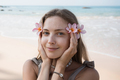Face of beautiful young adult blond woman holding flowers close to face at beach - PhotoDune Item for Sale