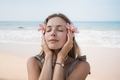 Beautiful blond woman holding flowers close to face with closed eyes at sea coast - PhotoDune Item for Sale