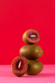 Still life of balancing red kiwis on a red background. The concept of fruits - PhotoDune Item for Sale