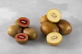 Red and gold kiwi whole and halves on a gray table. Different varieties of kiwi. - PhotoDune Item for Sale