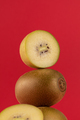 Still life of balancing golden kiwis on a red background. The concept of fruits - PhotoDune Item for Sale