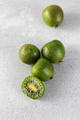 Mini kiwi on a gray table, whole and half. Tropical fruits. Kiwi berry. - PhotoDune Item for Sale
