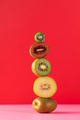 Still life with balancing kiwis of different varieties on a red. A balance of fruits, aart concept. - PhotoDune Item for Sale