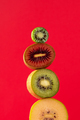Still life with balancing kiwis of different varieties on a red. A balance of fruits, art concept. - PhotoDune Item for Sale