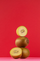 Still life of balancing golden kiwis on a red background. The concept of fruits - PhotoDune Item for Sale