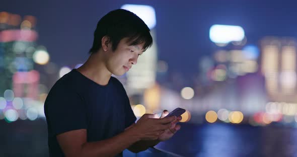 Young Man use of mobile phone in city at night