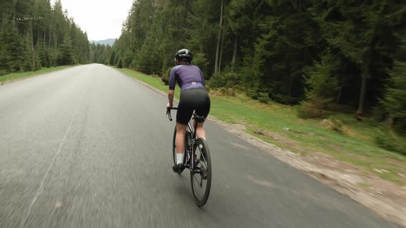 Cyclist riding bicycle out of saddle. Woman cycling on bike. Athlete training on bike