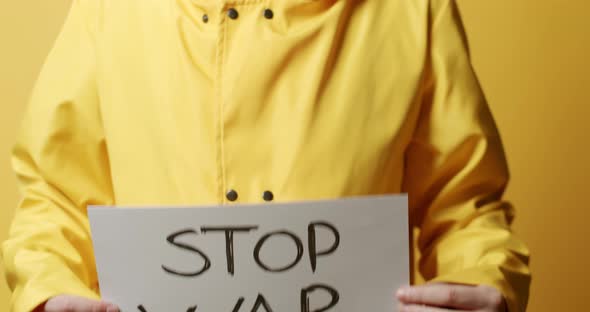 Person Holding a White Paper with a Message Stop War