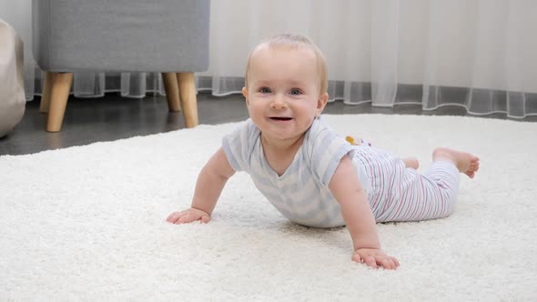 Happy Smiling Baby Boy Lying on Soft Carpet in Living Room