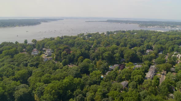 Aerial Pan of a Small Town Amongst Trees and Boats on Bay Seen from a Distance