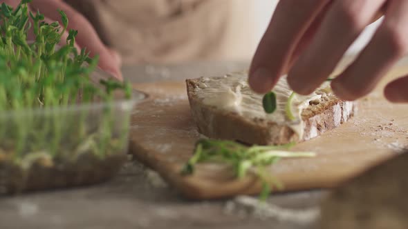 The Man Makes A Healthy Sandwich. A Slice Of Rye Bread With Cream Cheese On A Bamboo Cutting Board