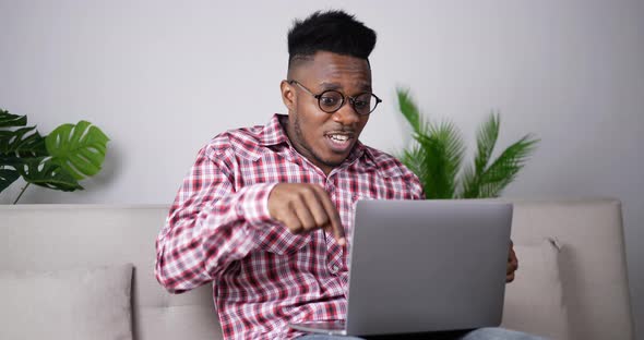 Stressed african man looking monitor on laptop with feeling upset