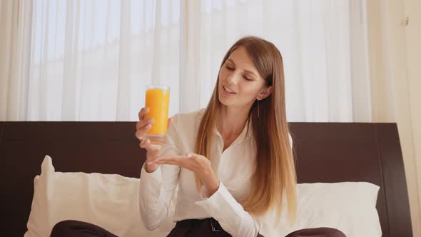 Woman Holding Glass of Orange Juice and Talking on Camera