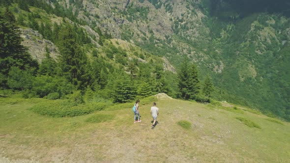 Two Hikers Couple Resting on the Top of the Mountain and Looking at the Valley Below