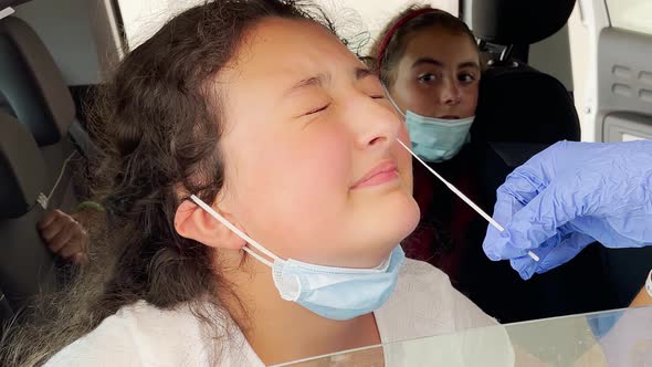 Pediatrician Taking Nasal Mucus Test Sample From Elementary Age Girl's Nose Performing Respiratory